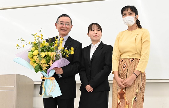 感謝のセレモニーでお礼の言葉を述べ、花束を贈る奨　学生代表ら